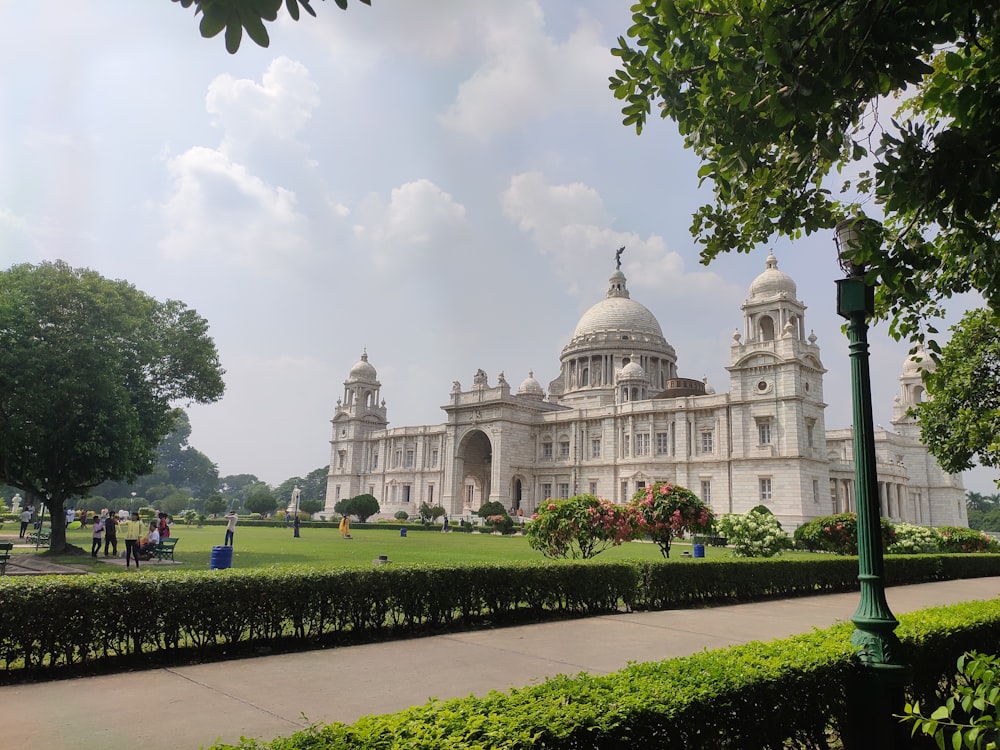 a large white building with a dome and a green lawn with Victoria Memorial Hall in the background