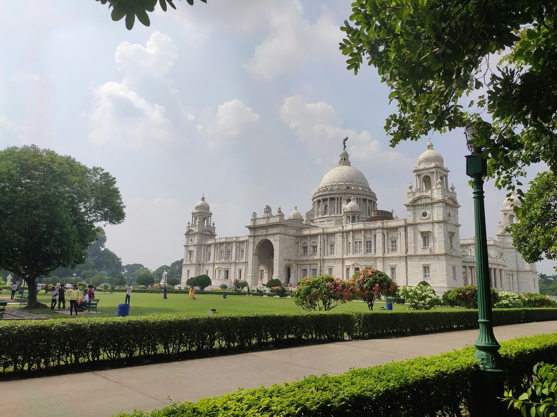a large white building with a dome and a green lawn with Victoria Memorial Hall in the background