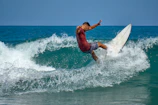 Action shot of a surfer wearing a redflip long-sleeve shirt paddling into a wave.