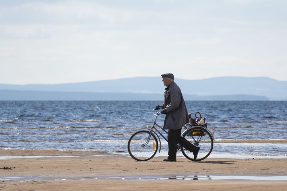 a man standing next to a bicycle on a beach