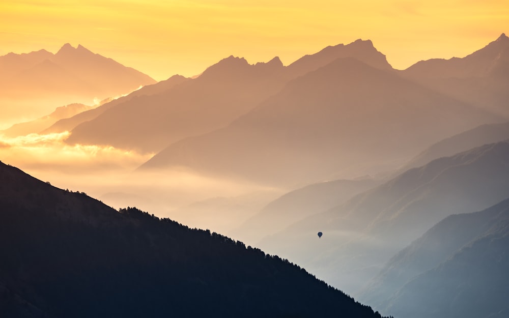 a hot air balloon flying over a mountain range