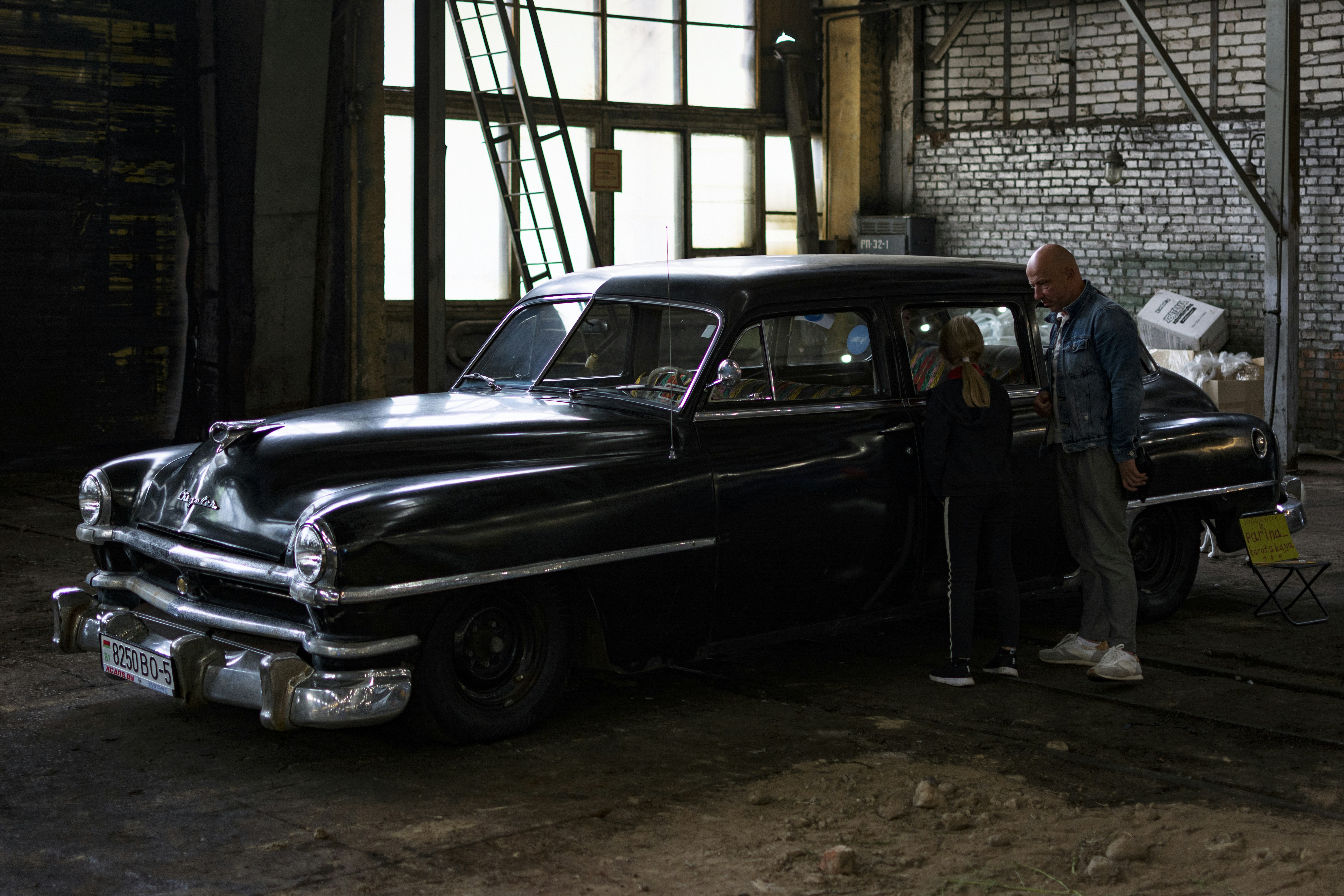Un homme et une femme debout à côté d’une voiture dans un garage