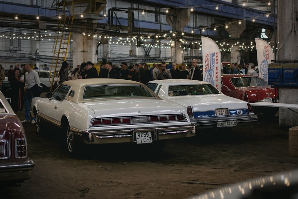 a group of cars parked in a showroom with people standing around