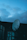 A satellite dish is prominently featured against a backdrop of a cloudy sky at dusk. The silhouette of a building and some foliage is visible in the foreground.