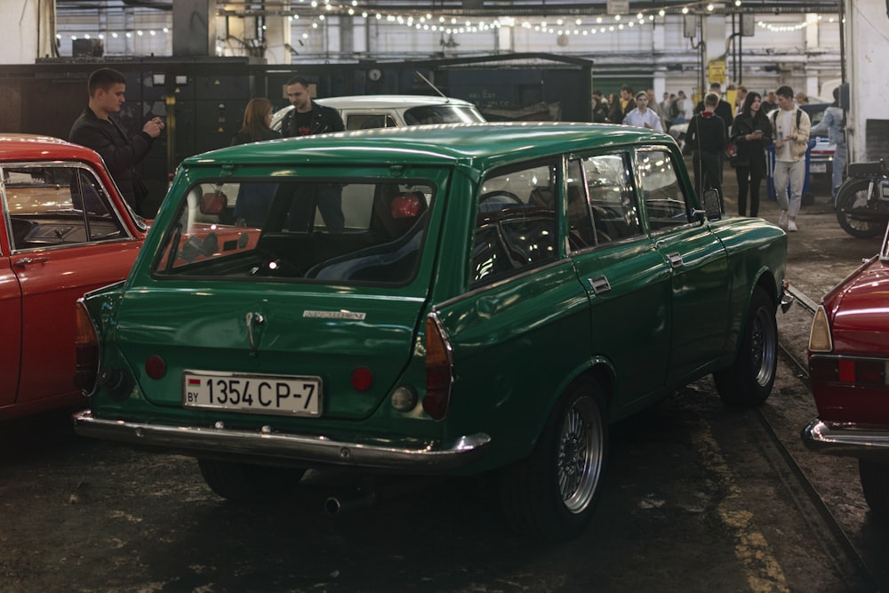 a green car parked in a showroom with people standing around