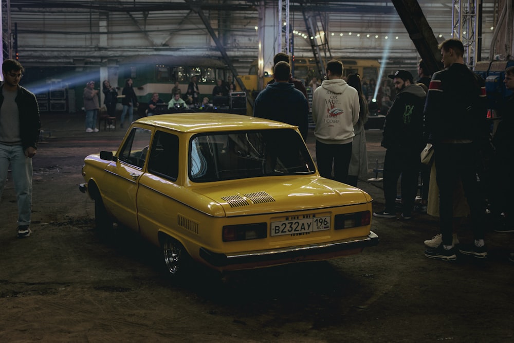 a yellow car parked in a building with people around it