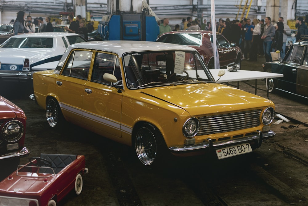 a yellow car parked in a showroom with other cars