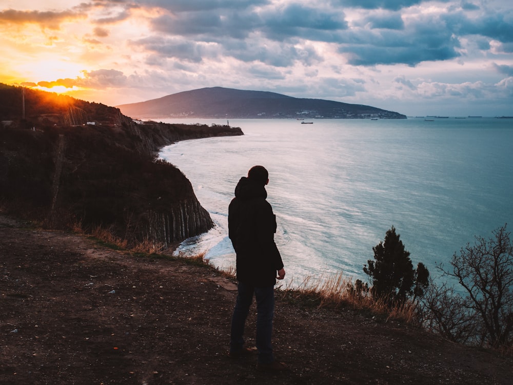 a person standing on a cliff looking at the water