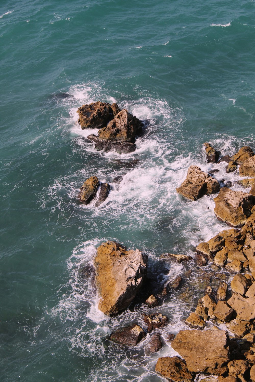 a rocky beach with a body of water in the background