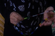 An artist carefully crafting a colorful bead necklace inspired by West African designs.