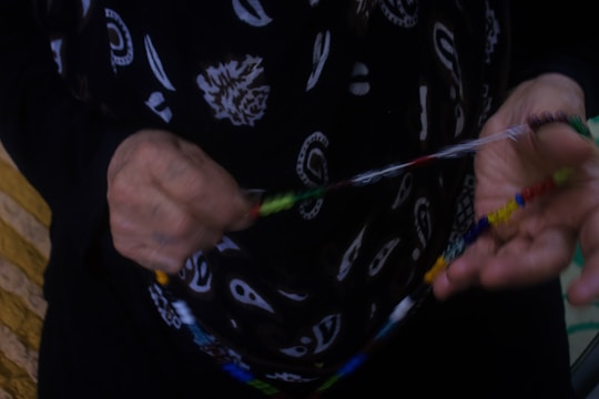Close-up of an artisan carefully threading rice beads onto a necklace.