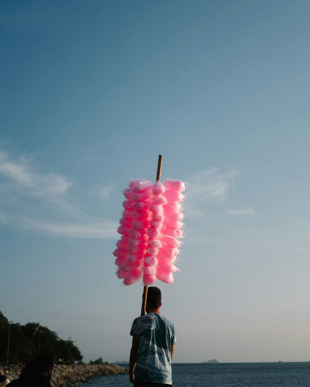 a person standing on a beach with a pink explosion in the sky