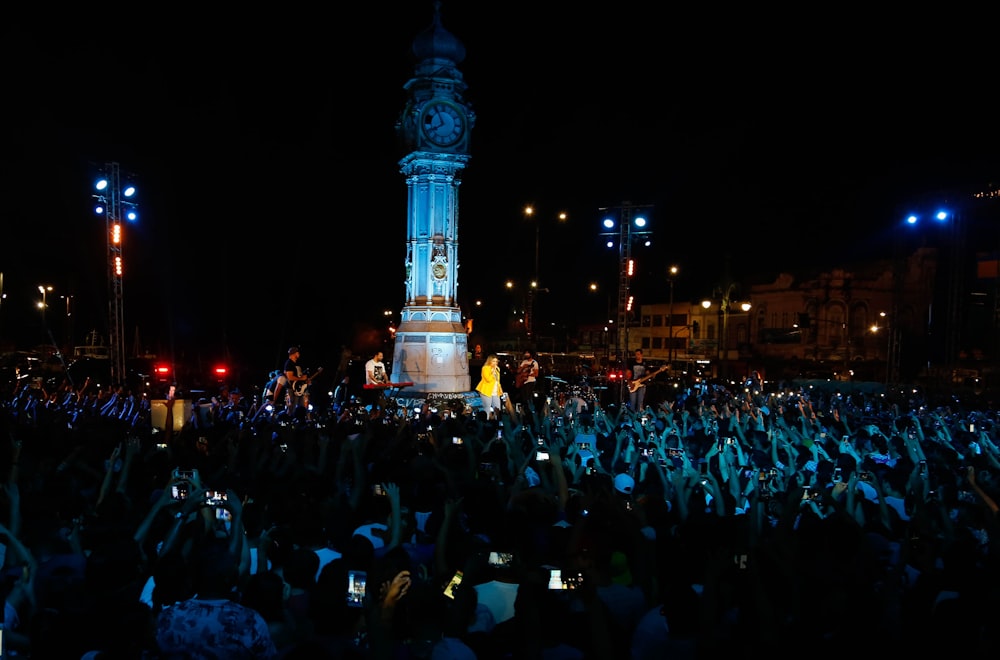a large crowd of people in front of a large clock tower