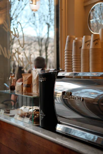 Display of coffee machines alongside stacks of disposable cups and plates in a cozy café setting.