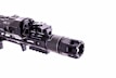 A close-up view of a firearm accessory with detailed engravings and mounted components, showcasing intricate metalwork and a tactical design.