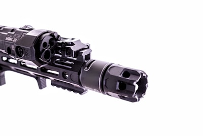 A close-up view of a firearm accessory with detailed engravings and mounted components, showcasing intricate metalwork and a tactical design.