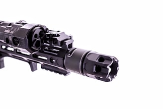 A close-up view of a firearm accessory with detailed engravings and mounted components, showcasing intricate metalwork and a tactical design.