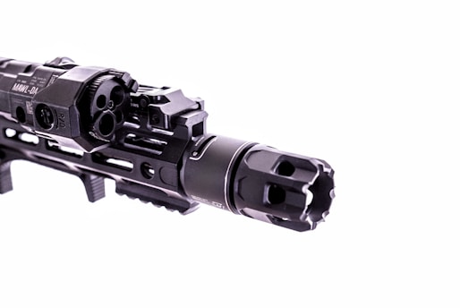 A close-up view of a firearm accessory with detailed engravings and mounted components, showcasing intricate metalwork and a tactical design.