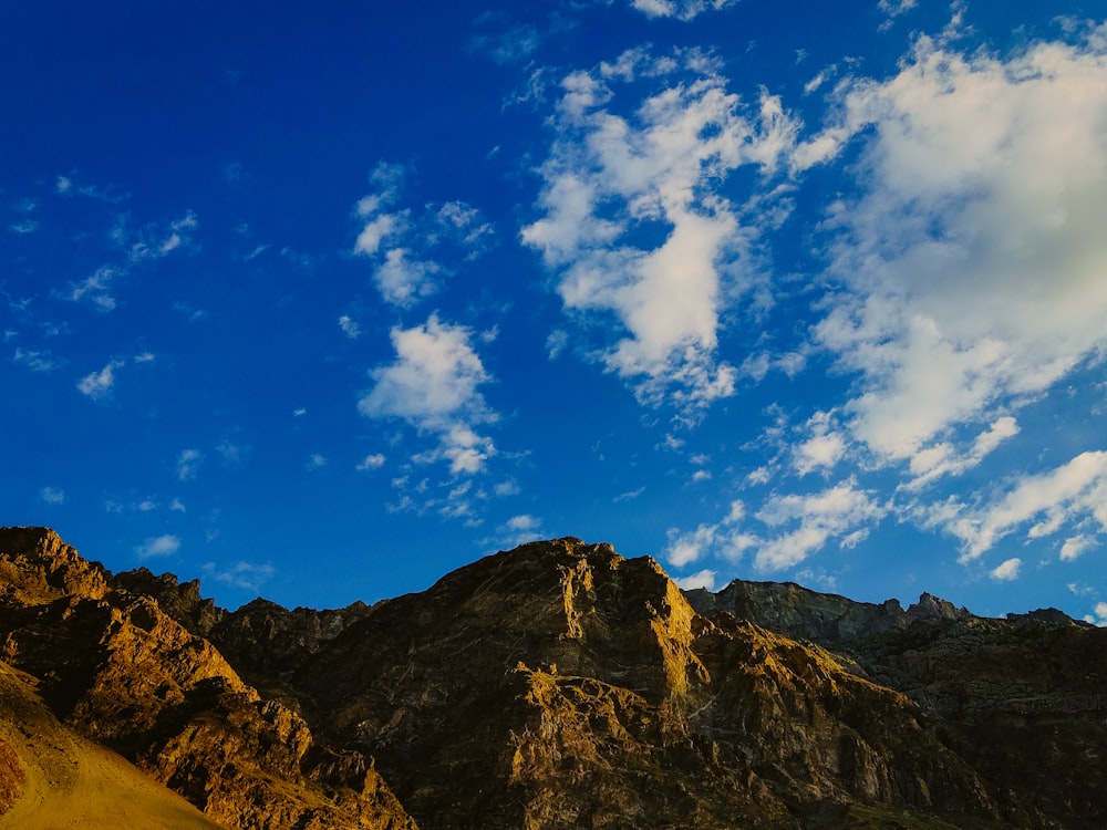 a rocky mountain with blue sky and clouds