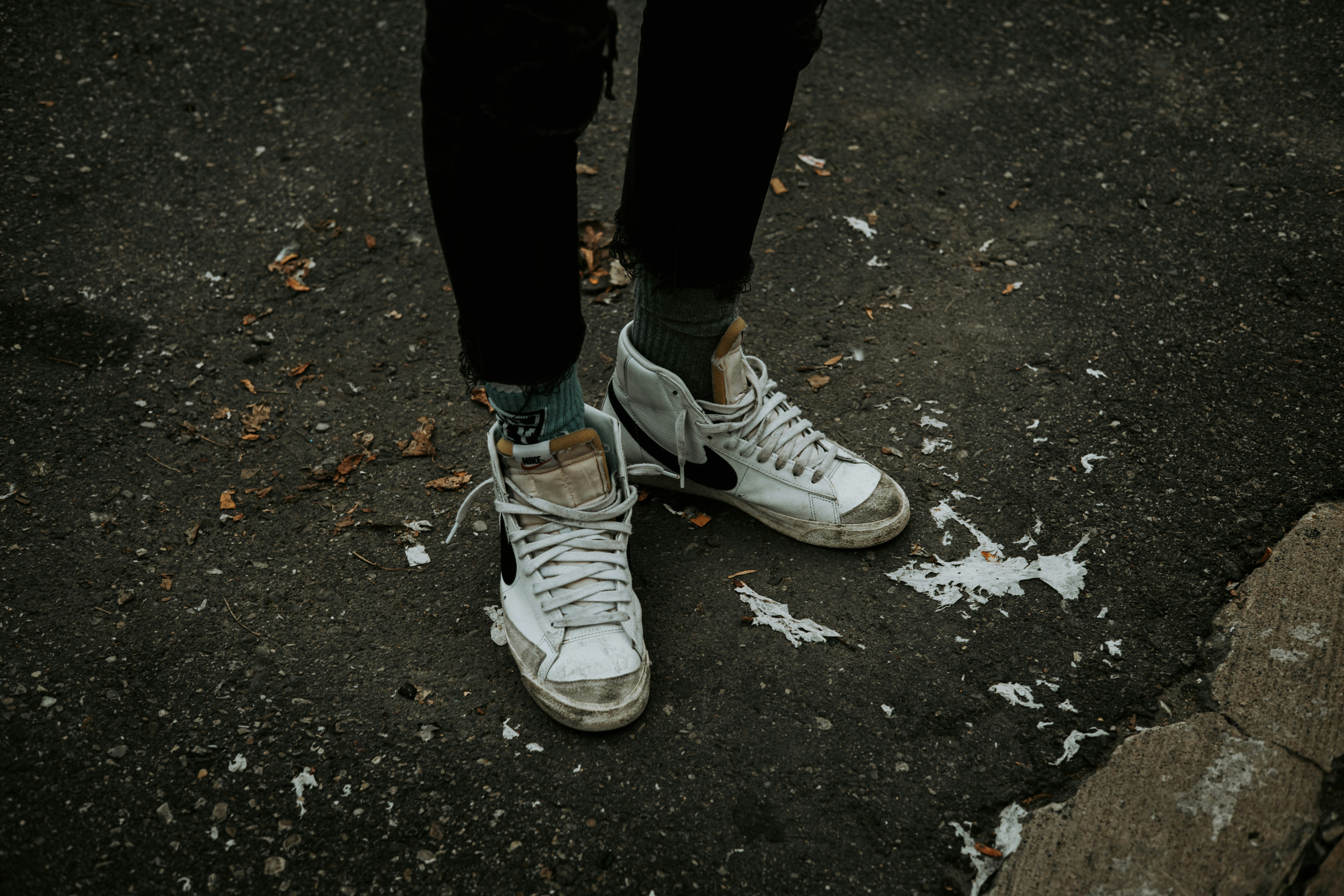 a person's feet in white shoes on a stone surface