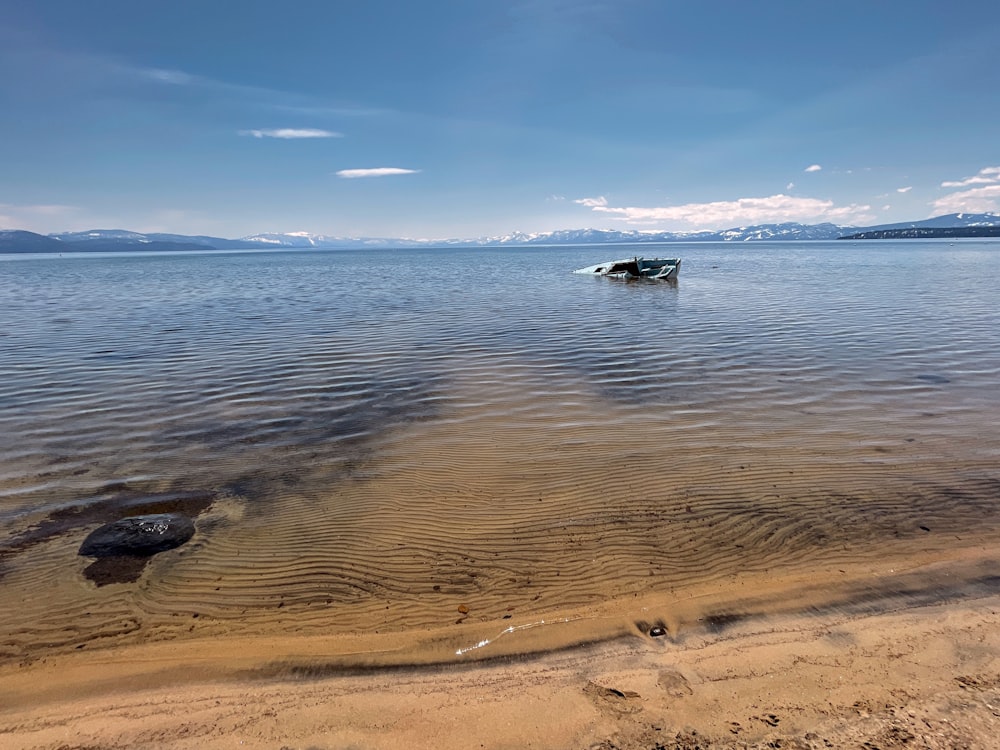 a sandy beach with a boat in the water