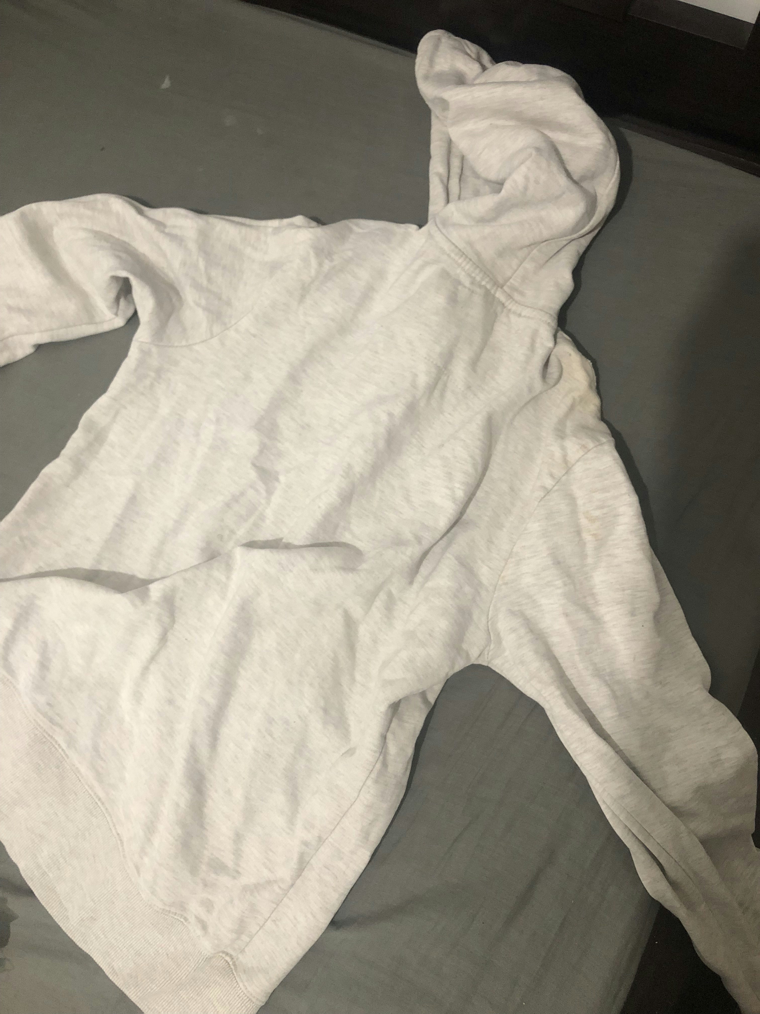 Dark grey university hoodie folded neatly on a shelf, minimal dark background