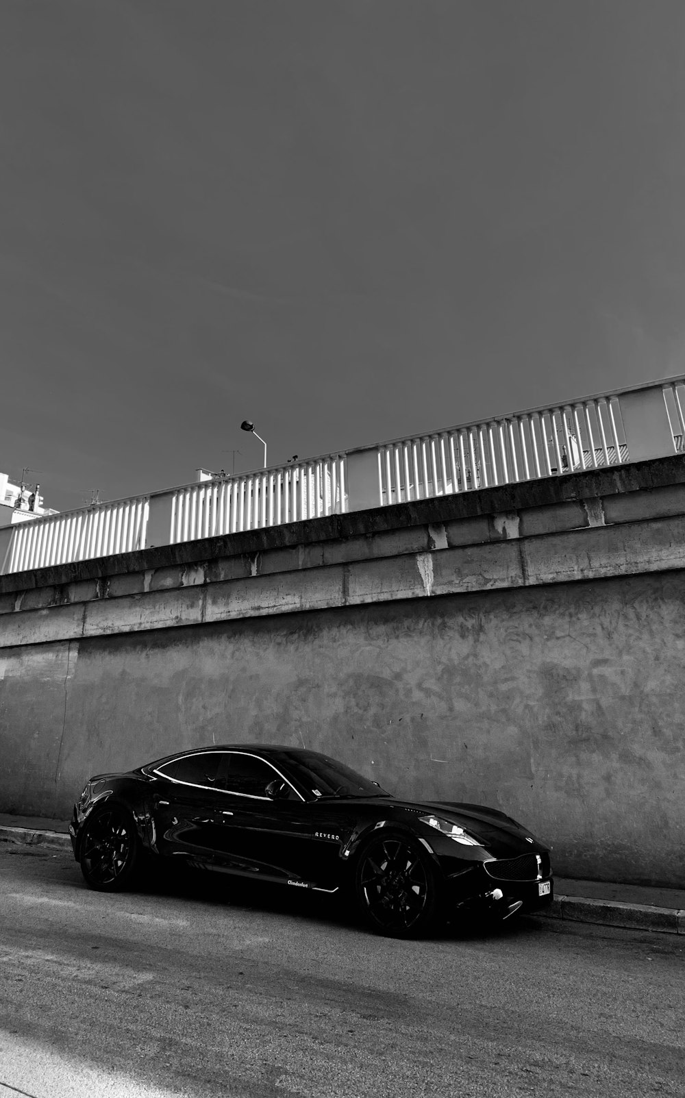 a black sports car parked on a road by a bridge