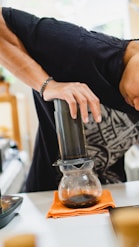 Aeropress brewer mid-press with dark coffee flowing into a mug.