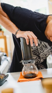 Aeropress brewer mid-press with dark coffee flowing into a mug.