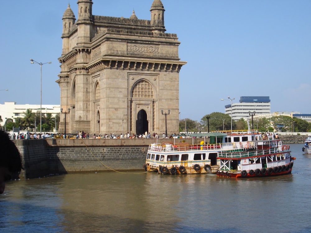 a group of boats on a river with India Gate in the background