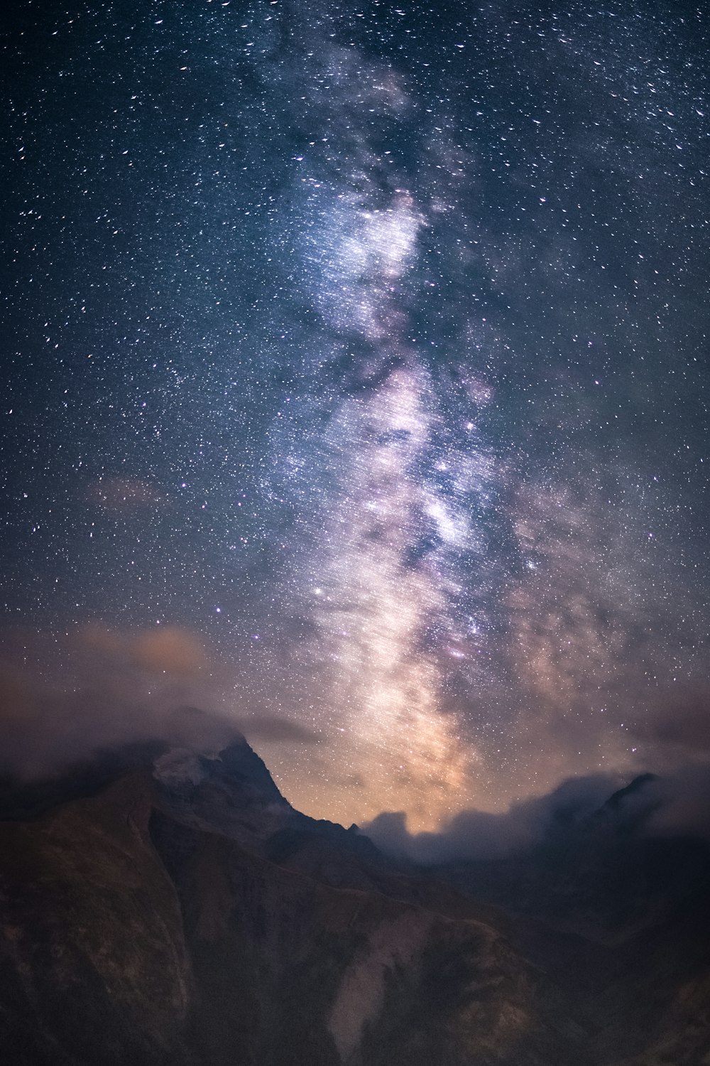 Un cielo notturno stellato sopra una catena montuosa