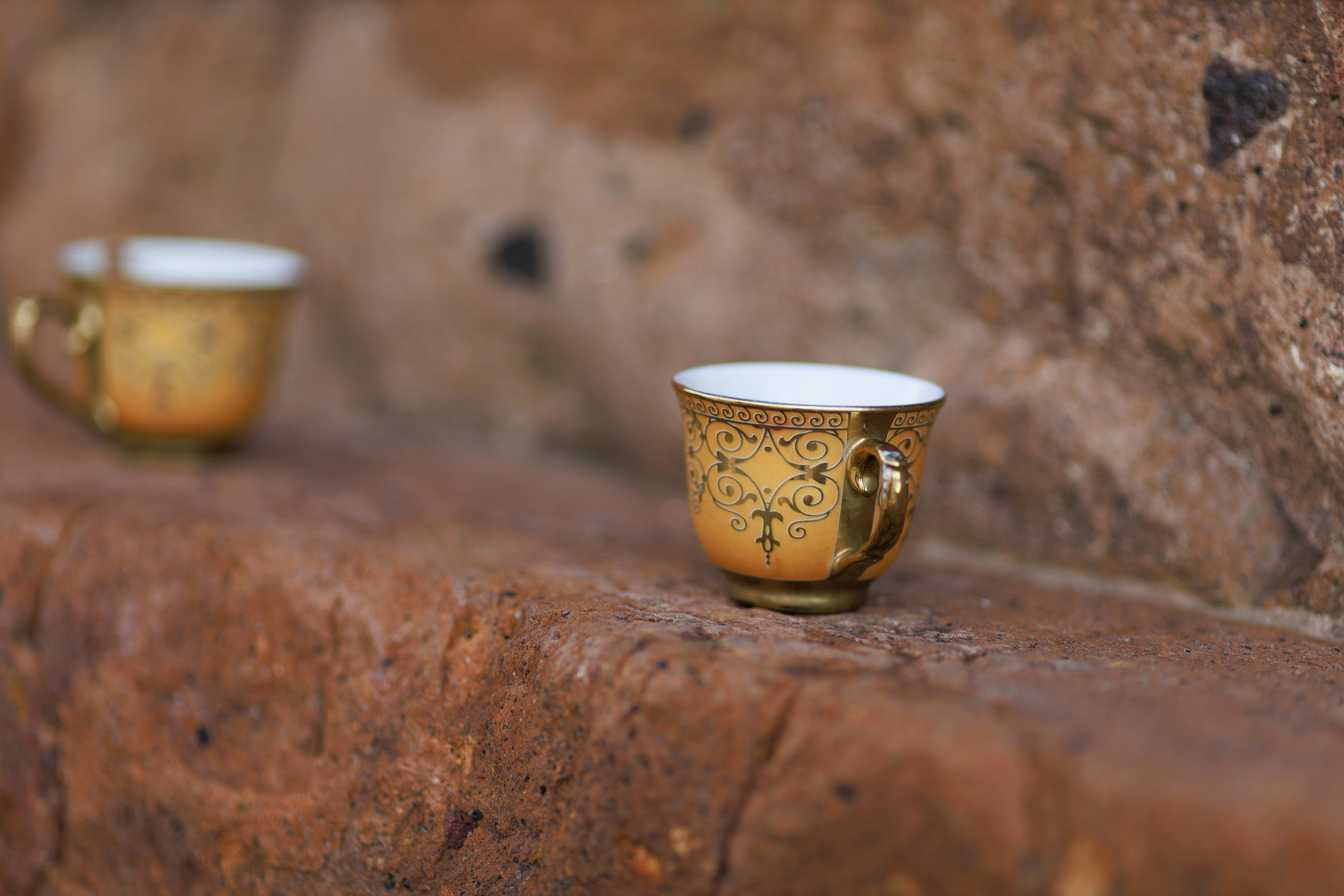 a cup and a glass on a rock