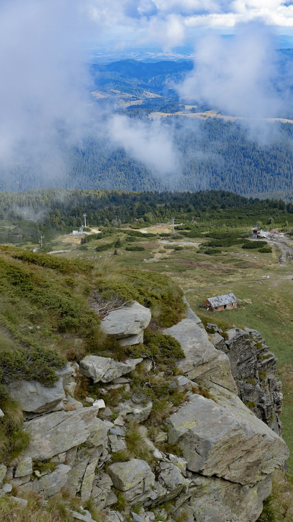 Ein felsiger Hang mit einem Haus und Bergen im Hintergrund