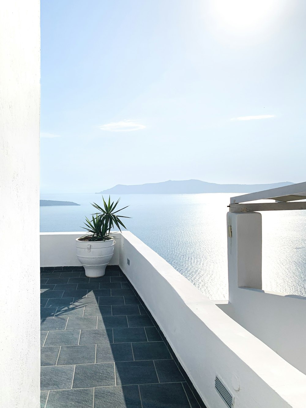 a white wall with a planter and a body of water in the background