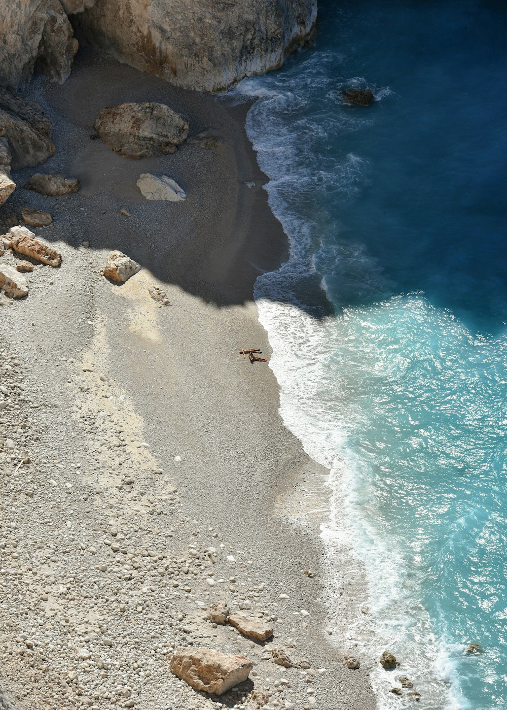 Una playa rocosa con un cuerpo de agua en el fondo