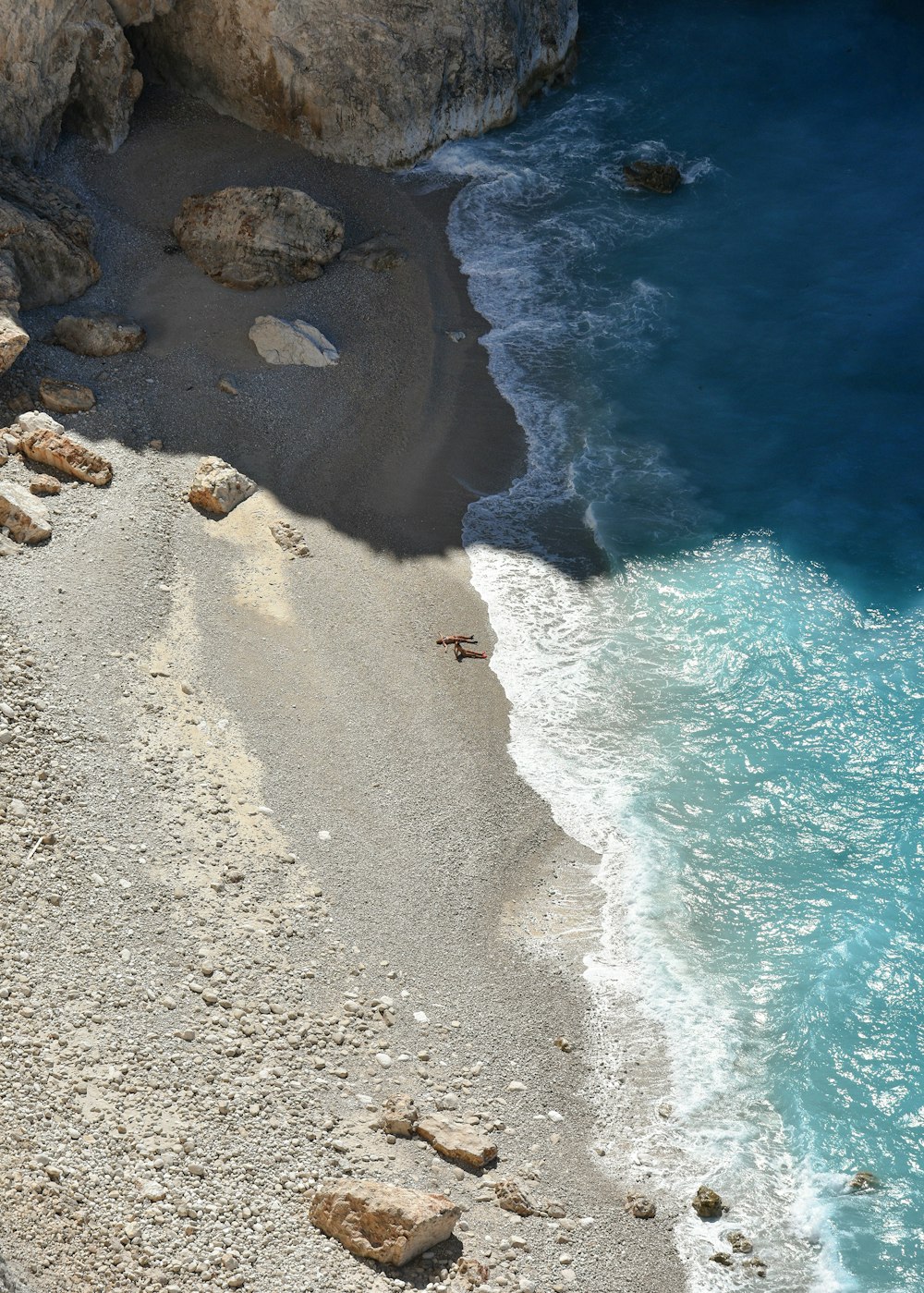 a rocky beach with a body of water in the background