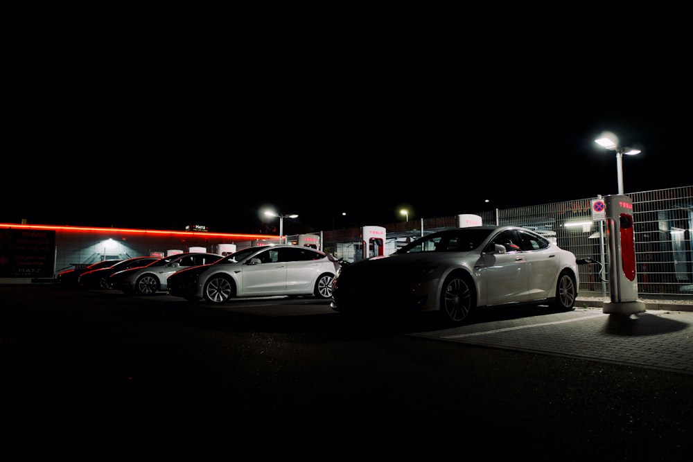 a group of cars parked in a parking lot at night