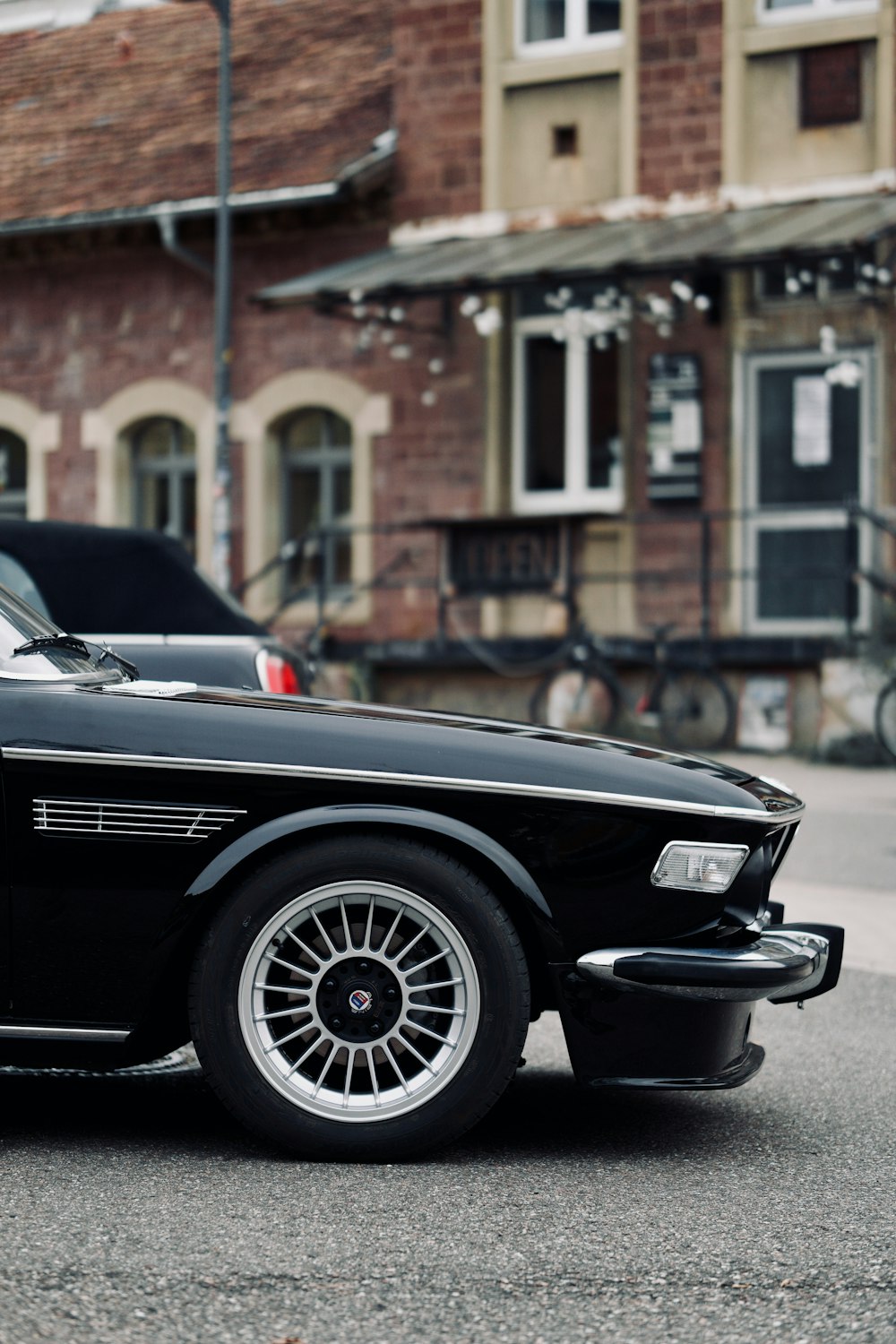 a black car parked in front of a brick building