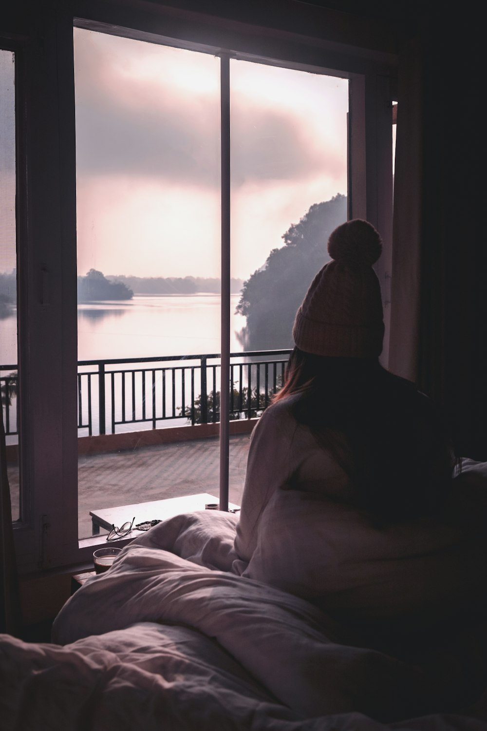 a couple of people sitting on a bed looking out a window