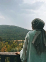 a person standing on a balcony overlooking a forest