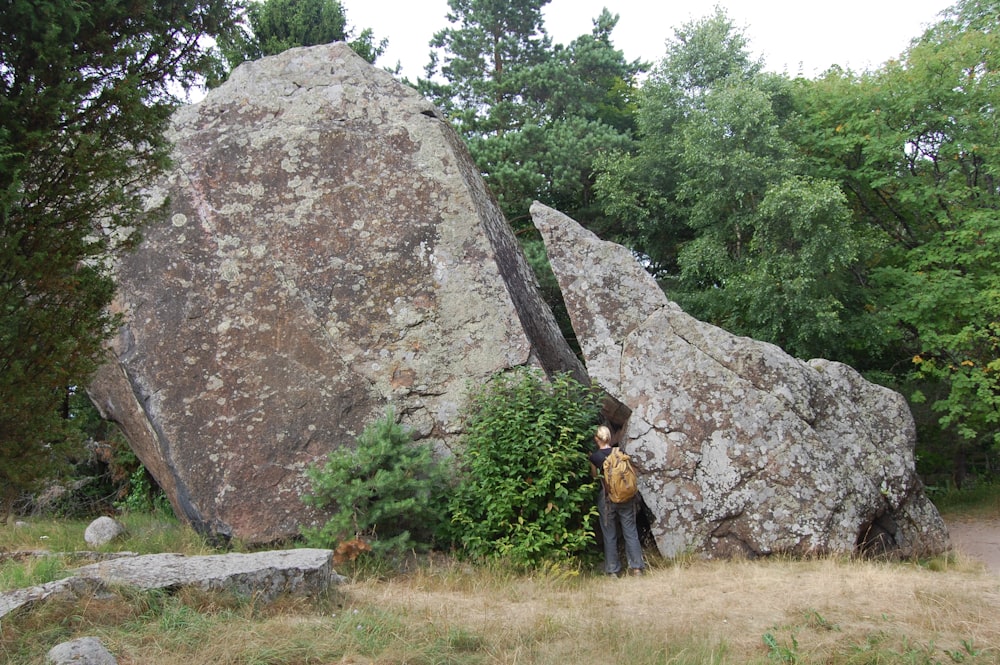a person standing next to a large rock
