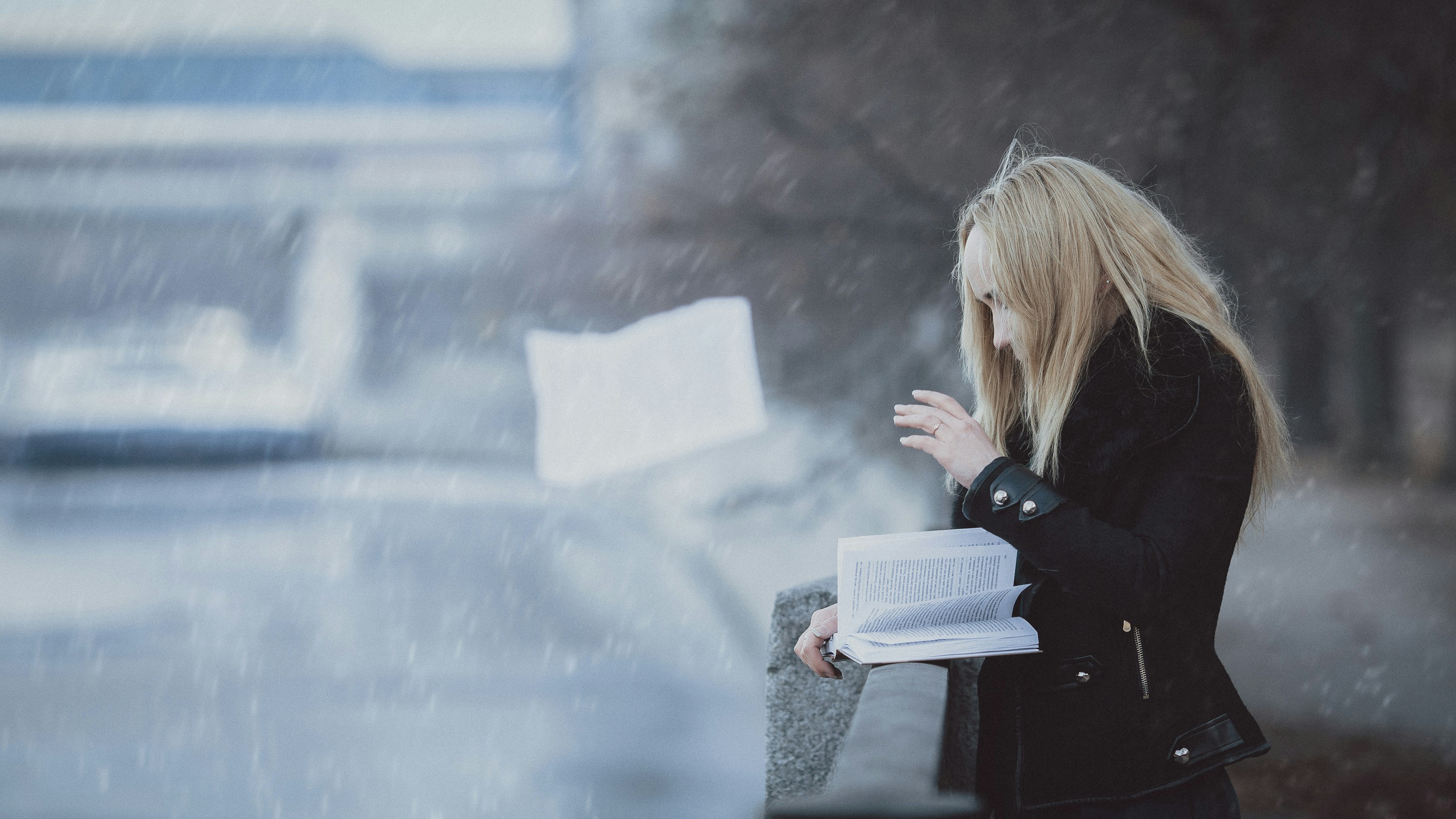 Woman reading by a grey rainy window