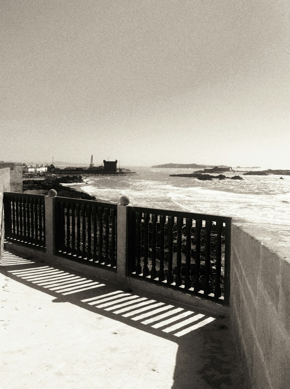 a black and white photo of a pier and a lighthouse