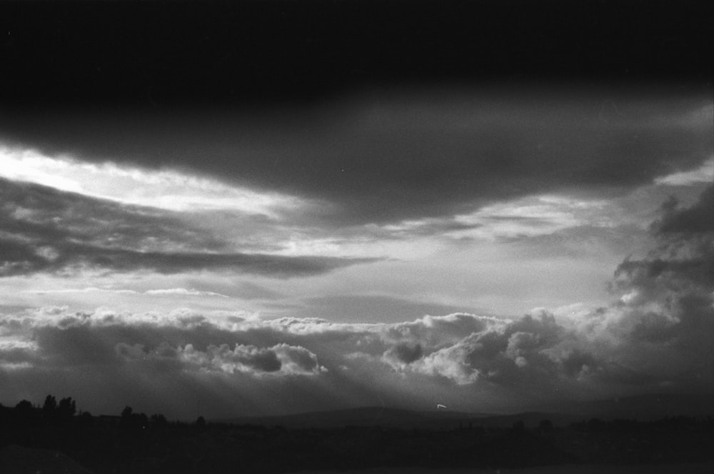 a black and white photo of a cloudy sky with a few trees