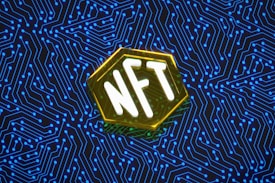 An abstract digital artwork featuring the letters 'NFT' in bold white typography, set within a hexagonal shape with a glowing yellow outline. The background consists of an intricate pattern of blue circuit lines on a dark backdrop, suggesting a theme of technology or the digital realm.
