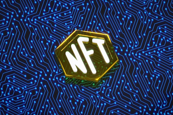 An abstract digital artwork featuring the letters 'NFT' in bold white typography, set within a hexagonal shape with a glowing yellow outline. The background consists of an intricate pattern of blue circuit lines on a dark backdrop, suggesting a theme of technology or the digital realm.