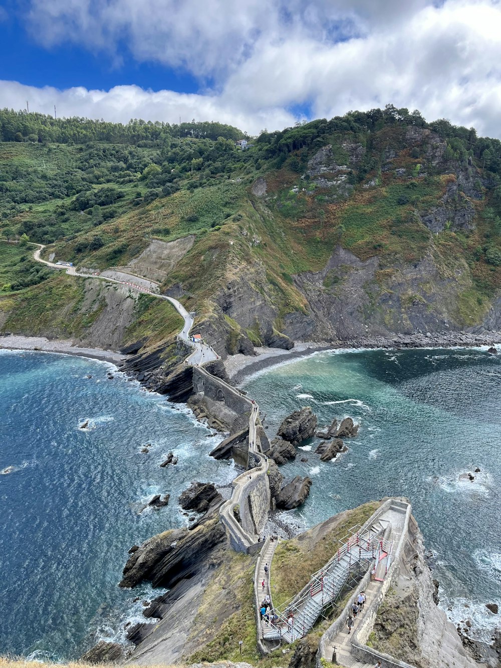 a rocky beach with a road and trees on the side