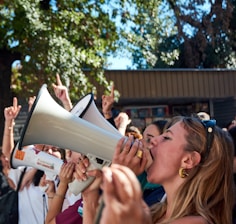 A crowd gathered around loudspeakers as messages call out deceptive businesses in Georgia.