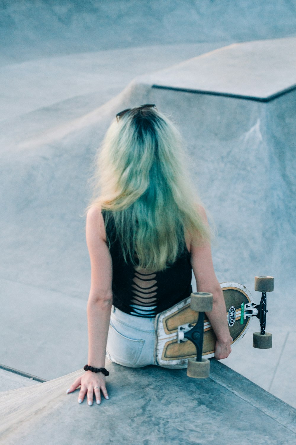 a person with long hair sitting on a skateboard