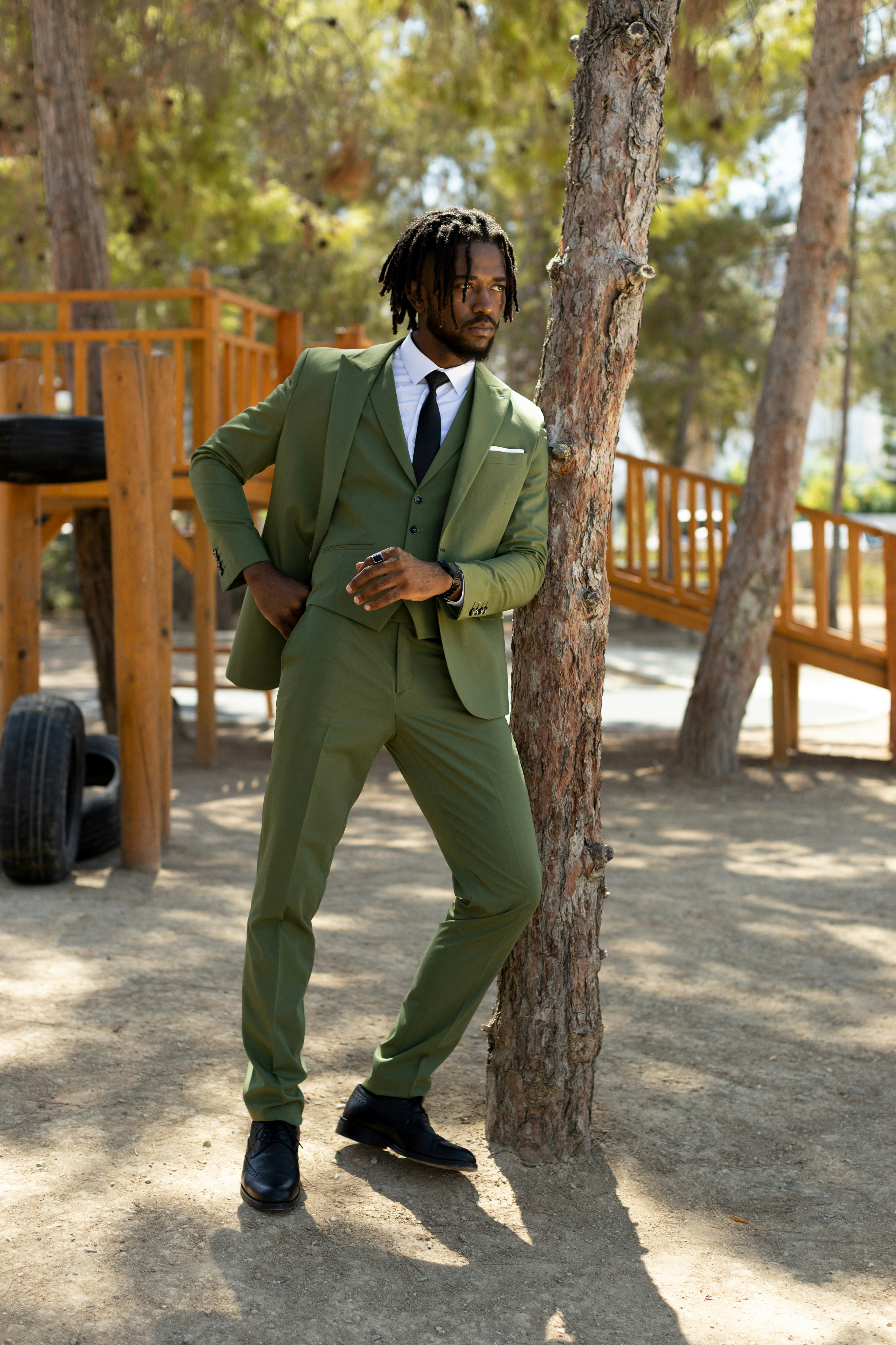 a man in a suit standing by a tree